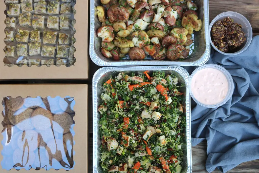 trays of potatoes, sauce, salad, and cookies