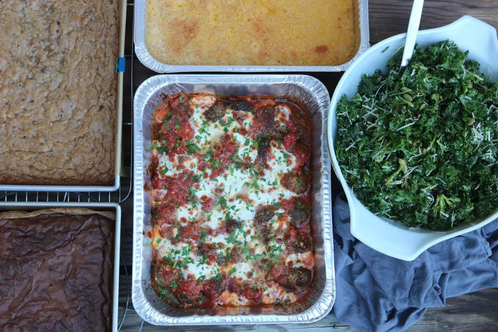 prepared pans of desserts, polenta, meatballs, and salad